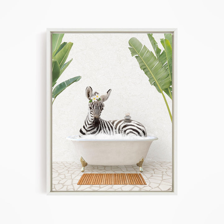 A zebra is sitting in a white bathtub, surrounded by tropical plants and a wooden mat on the floor.