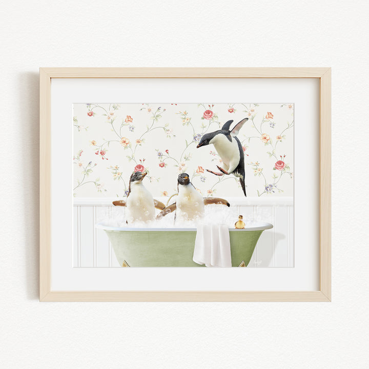 A framed image depicting three penguins sitting in a green bathtub, with a floral wallpaper in the background.