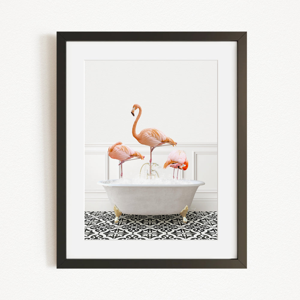 A framed image depicting three flamingos standing in a white bathtub on a black and white patterned floor.