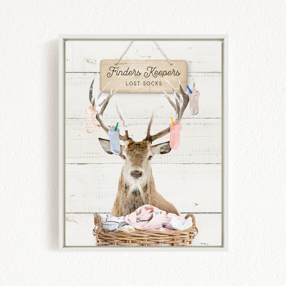 A deer with antlers is sitting in a basket filled with socks, with a sign above that says "Finders Keepers Lost Socks".