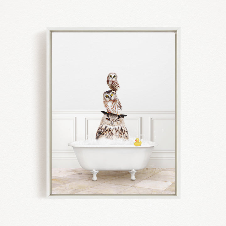 A white bathtub filled with water, with three owls sitting on top of it. One of the owls has a yellow rubber duck floating in the water.