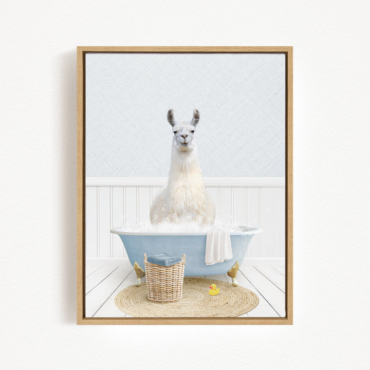 A white llama sitting in a blue bathtub filled with bubbles, surrounded by a basket of toys and a yellow rubber duck.