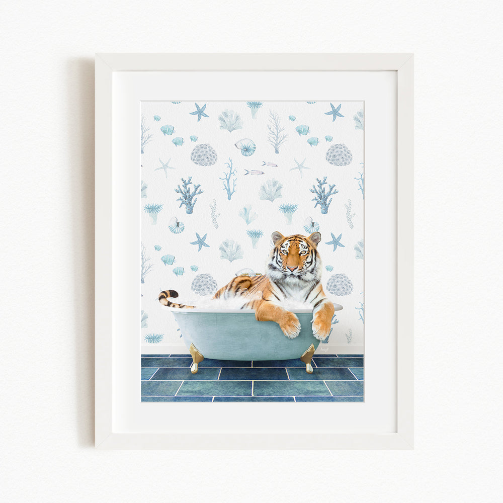 A tiger is sitting in a blue bathtub, surrounded by a pattern of blue and white seashells and starfish on the wall behind it.