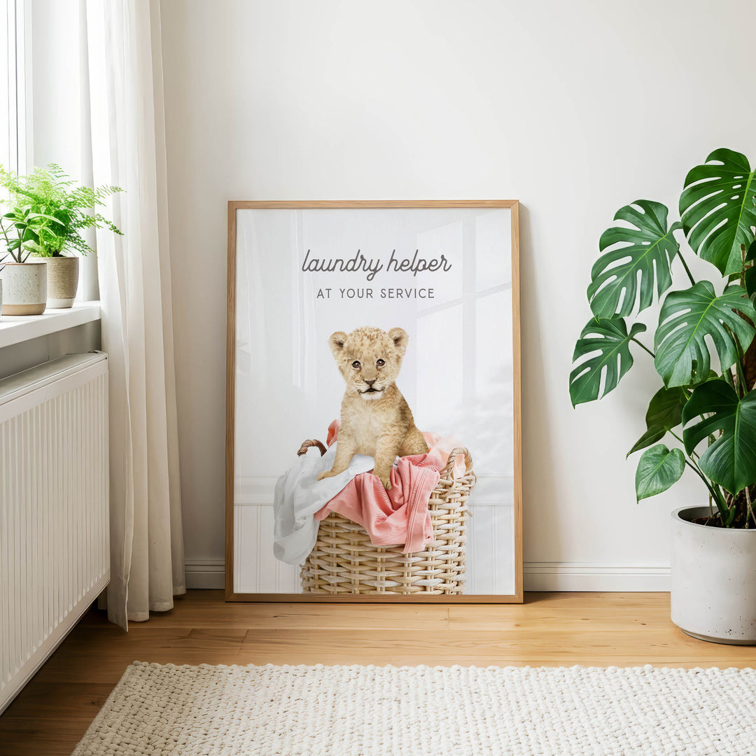 A framed poster with a lion sitting in a basket, accompanied by the text "laundry helper at your service".