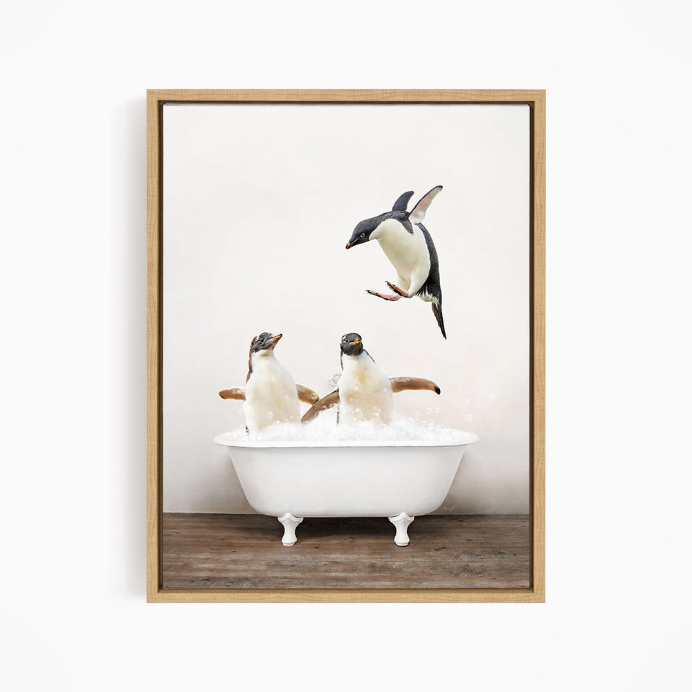 A framed image depicting three penguins sitting in a white bathtub, with one penguin flying towards the tub.