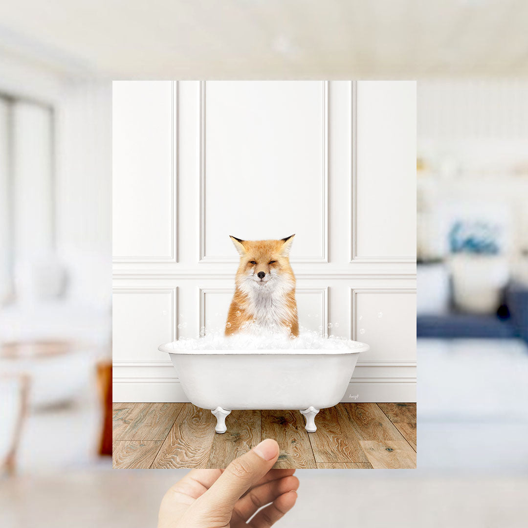 A hand holds up a photograph of a fox sitting in a bathtub filled with bubbles, creating a whimsical and playful scene.