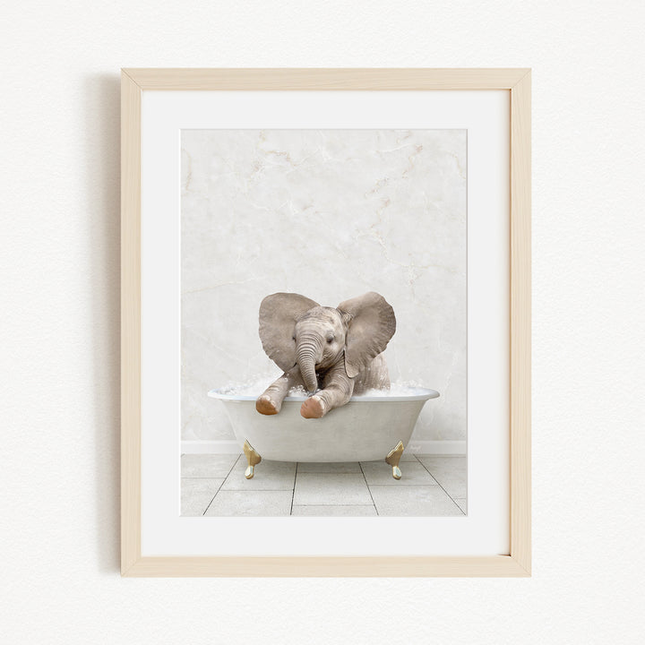 A baby elephant sitting in a white bathtub, with its trunk raised and ears flapping, against a white marble wall.