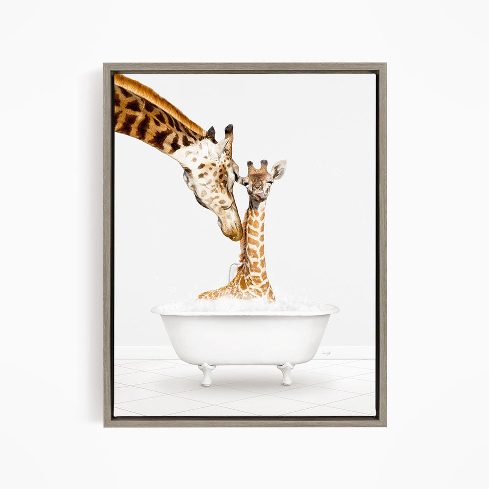 A mother giraffe and her baby giraffe are sitting together in a white bathtub, with the mother gently licking her baby.