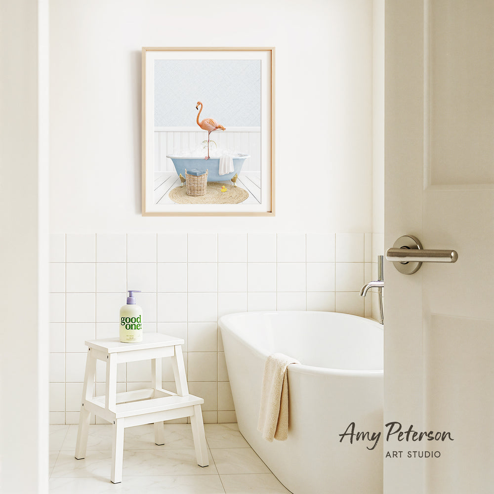 a bathroom with a white bathtub, a stool, and a framed picture of a flamingo on the wall.