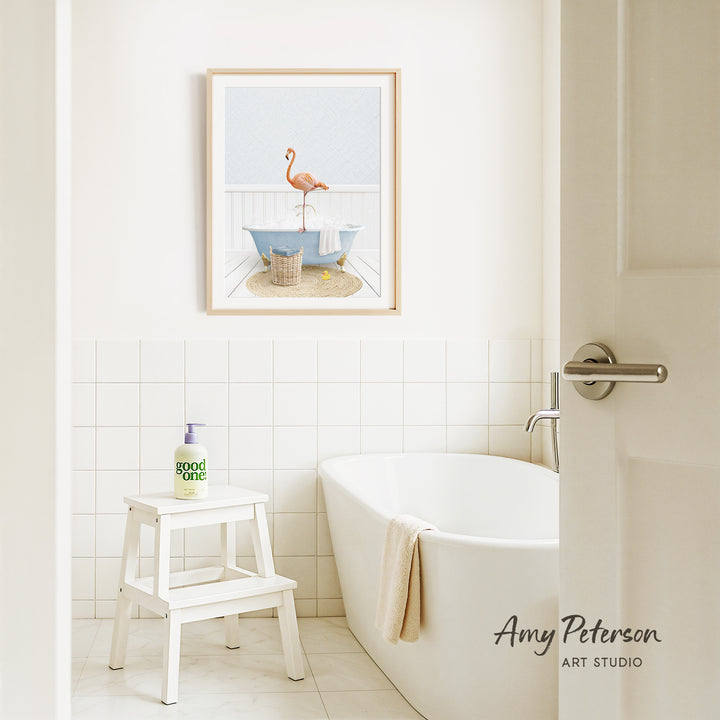 a bathroom with a white bathtub, a stool, and a framed picture of a flamingo on the wall.