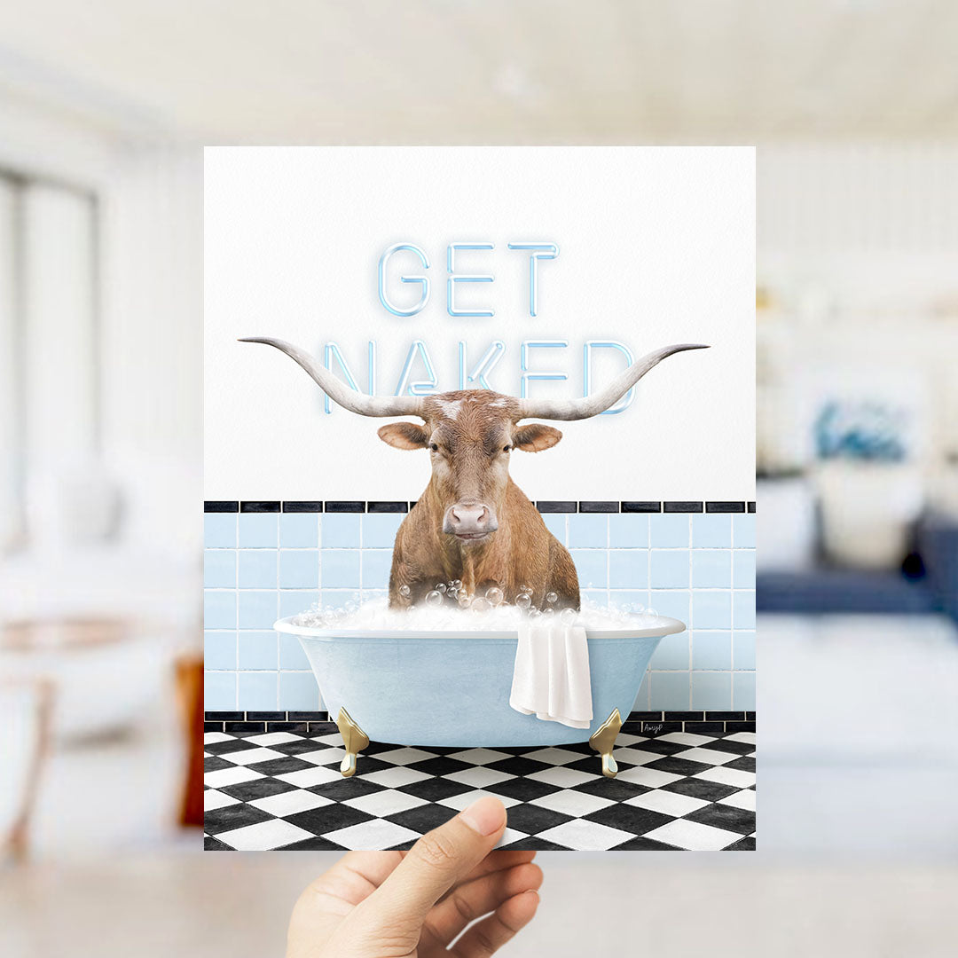 A hand holding a printed image of a bull with the text "GET NAKED" on a bathroom wall.