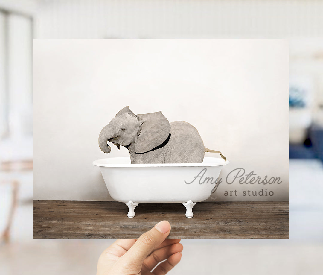 a person holding up a card with an elephant in a bathtub