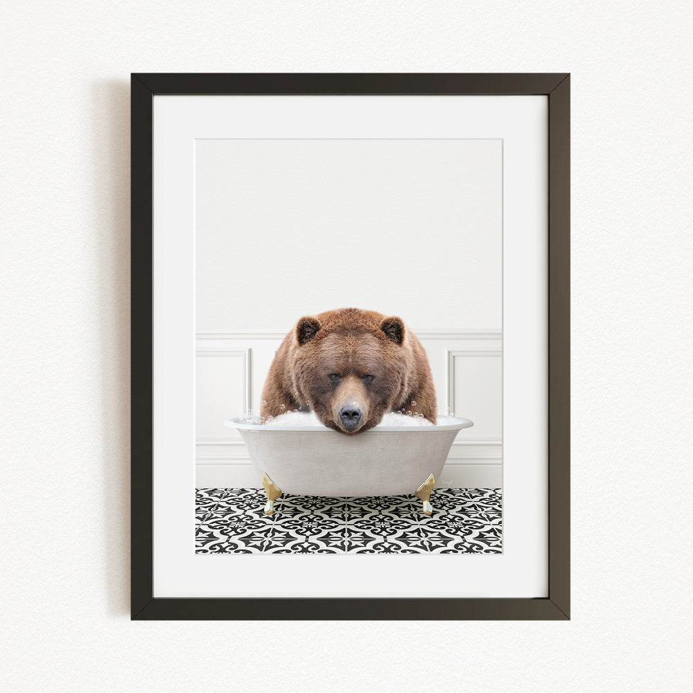 A brown bear is sitting in a white bathtub filled with bubbles, resting its head on the edge of the tub.