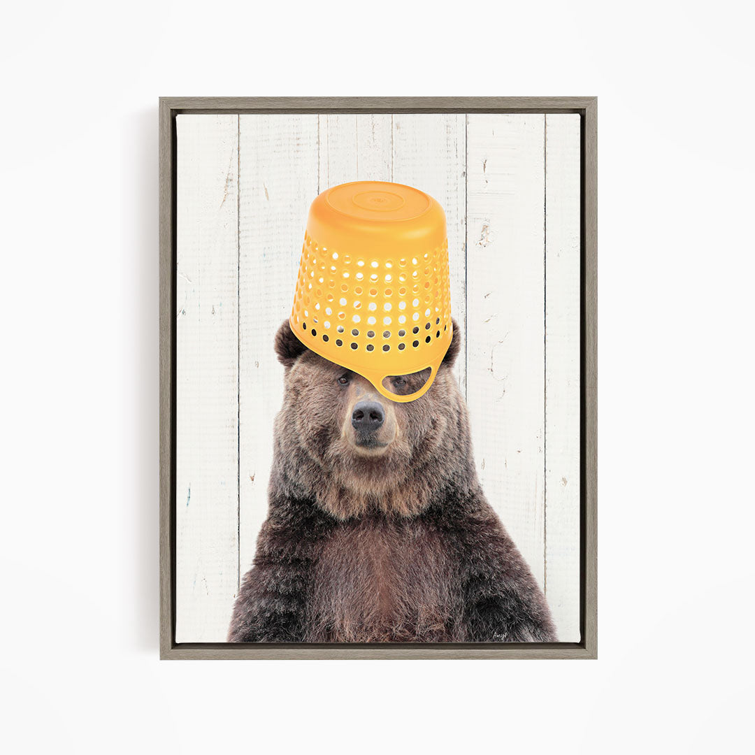 A brown bear wearing a yellow plastic bucket hat, with its eyes partially obscured by the hat.
