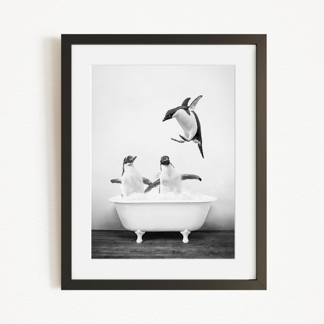 A black and white photograph of three penguins in a bathtub, with one penguin flying towards the others.