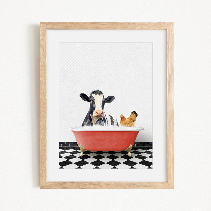 A framed image depicting a cow and a chicken relaxing in a red bathtub filled with water, set against a black and white checkered floor.