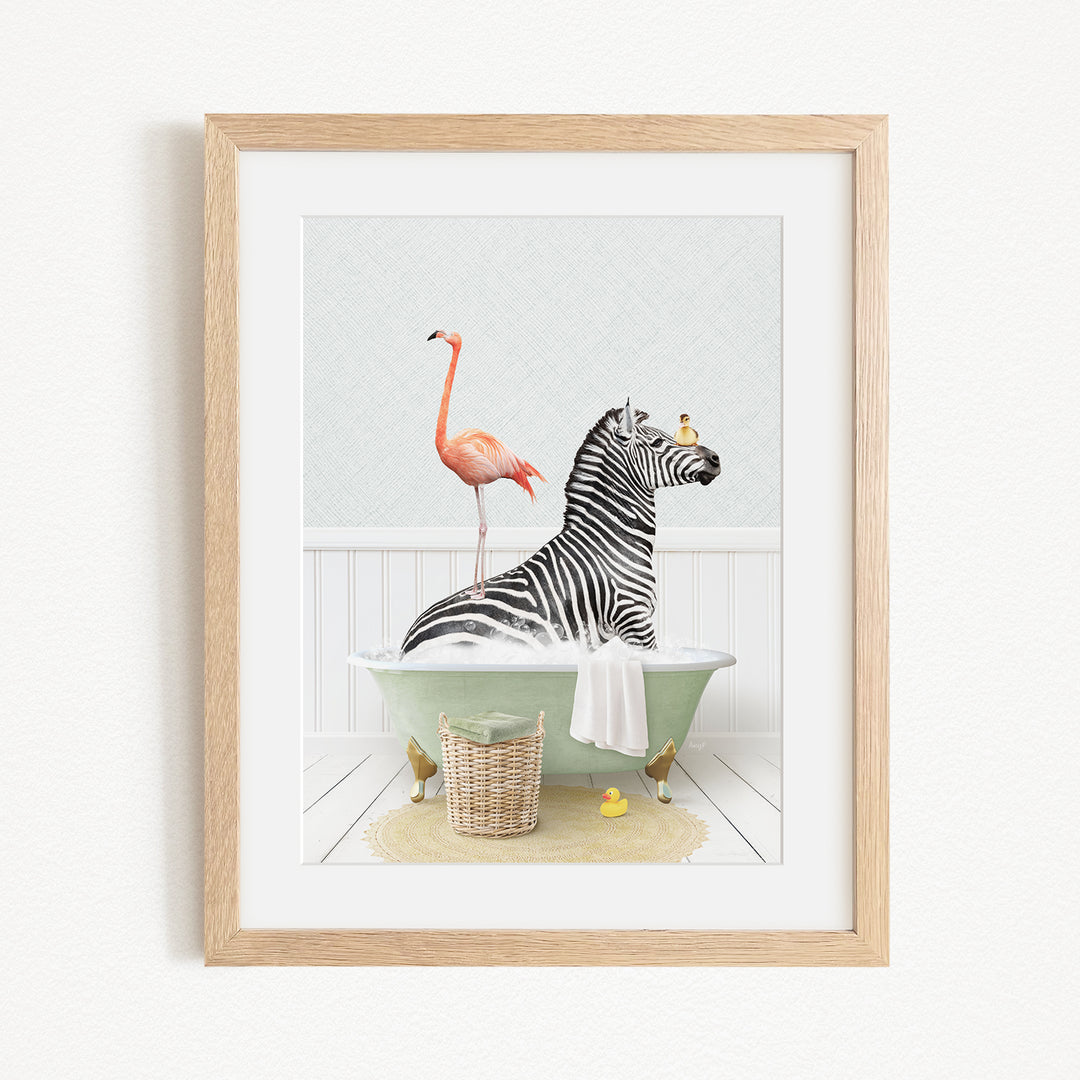 A framed image depicting a zebra sitting in a bathtub, with a flamingo standing on one leg and a basket of rubber ducks nearby.
