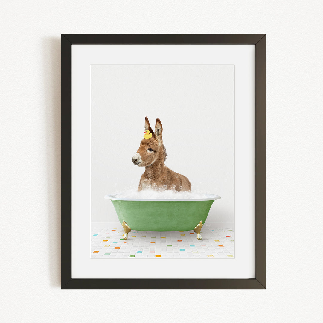 A donkey is sitting in a green bathtub filled with bubbles, with a yellow rubber duck floating on the water.