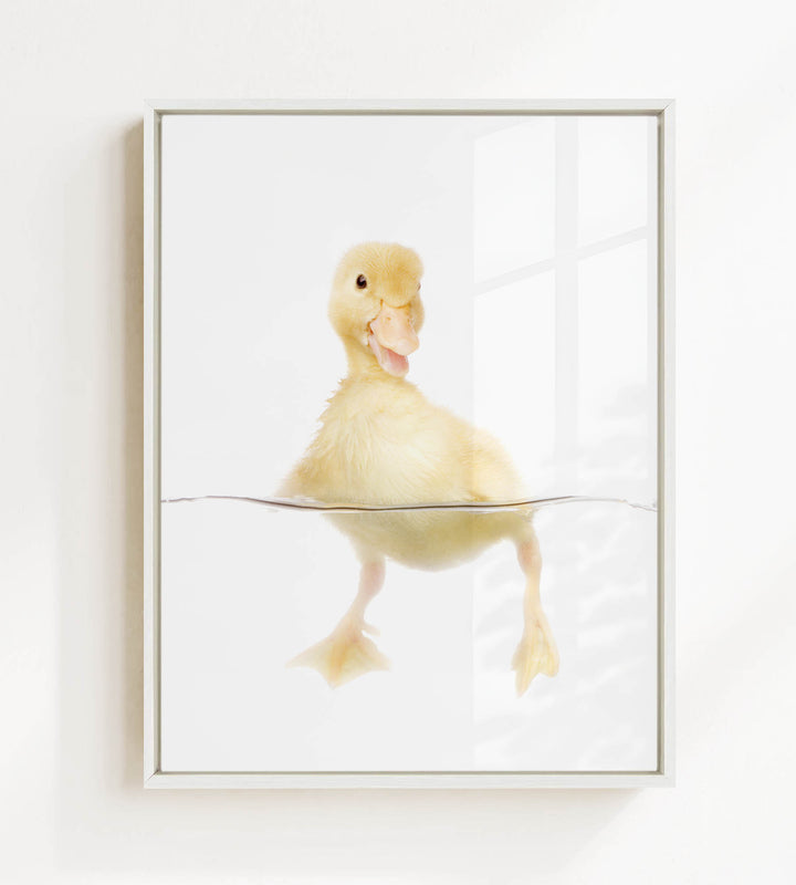 A cute yellow duckling swimming in a clear container, with its head and feet visible above the water's surface.