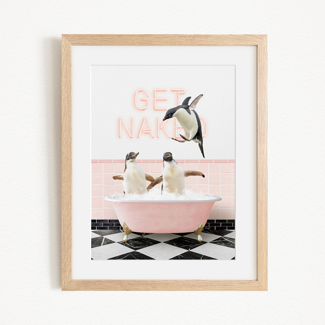 A framed image depicting two penguins sitting in a pink bathtub, with one penguin jumping out of the tub and the other penguin sitting in the tub. The background features a pink wall with a neon sign that says "GET NAKED".