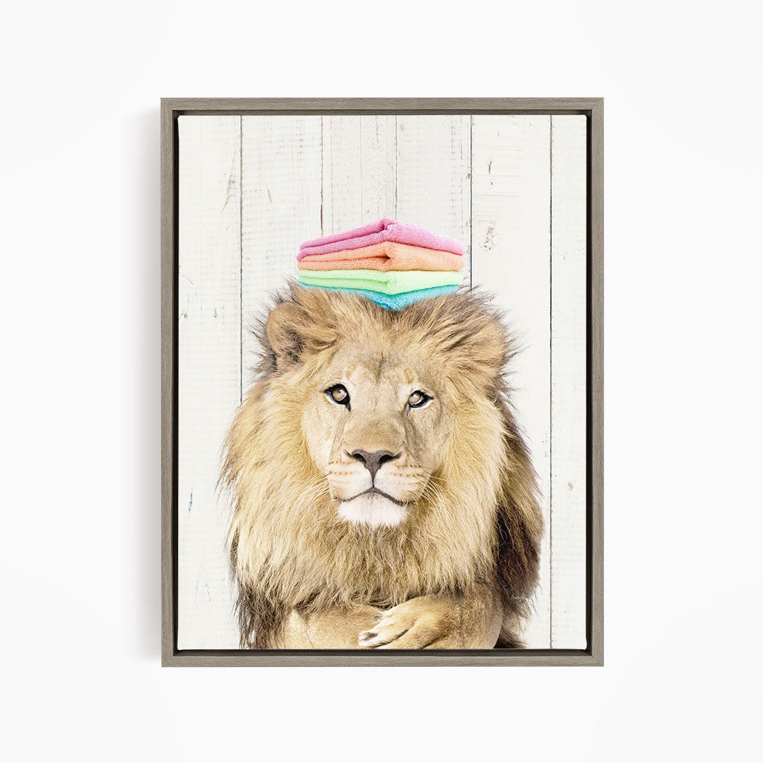 A lion with a stack of colorful towels on its head, looking directly at the camera.