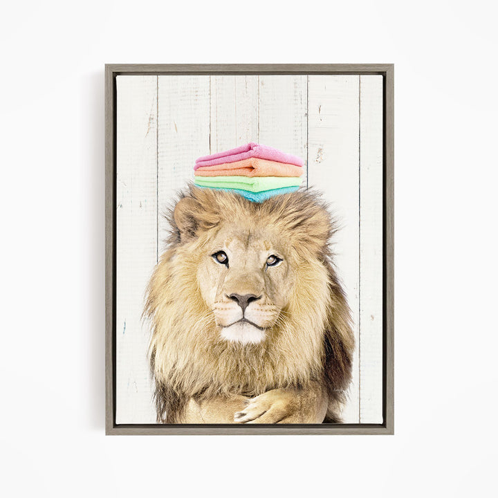 A lion with a stack of colorful towels on its head, looking directly at the camera.