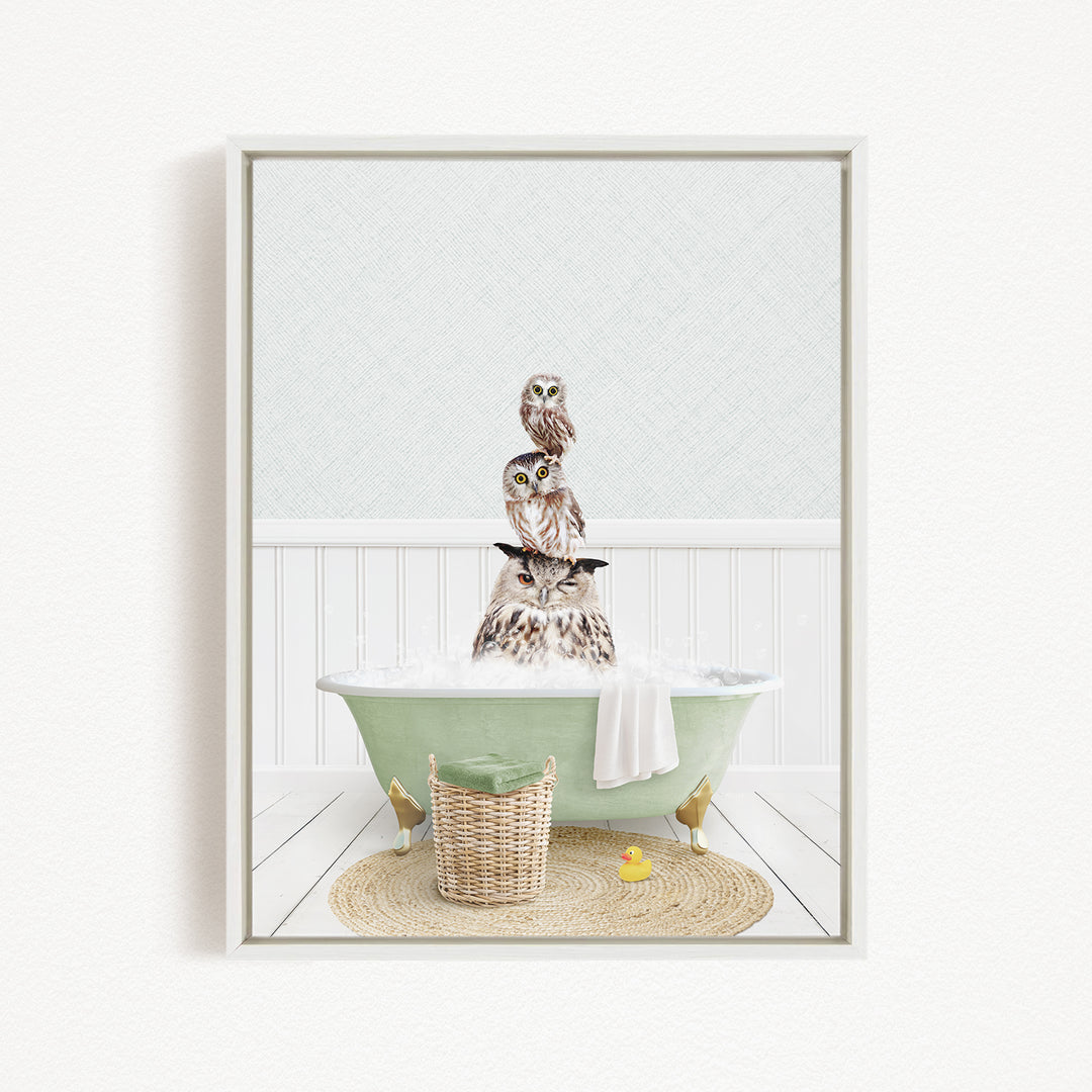 A framed image depicting a group of owls sitting in a green bathtub filled with bubbles, surrounded by a basket, a rubber duck, and a towel.