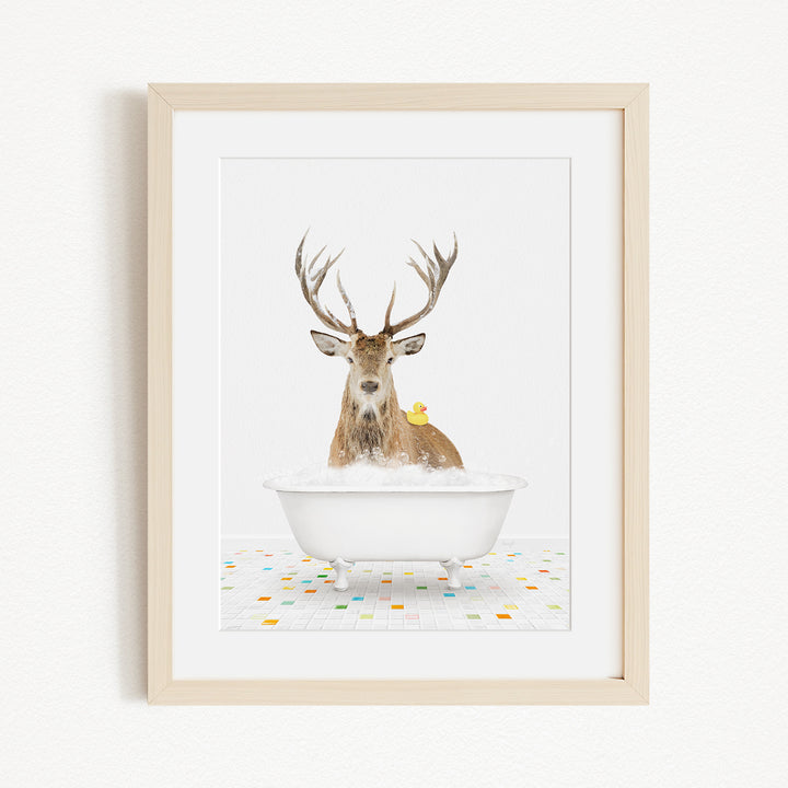 A deer with antlers is sitting in a white bathtub, with a yellow duck perched on its back.