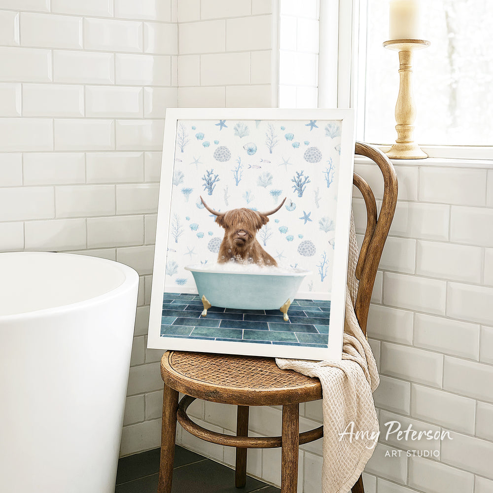 A framed image of a bull with horns sitting in a bathtub, surrounded by blue and white floral patterns, is displayed on a wooden chair in a bathroom setting.