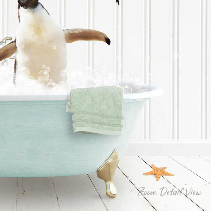 A penguin standing in a bathtub filled with bubbles, with a towel and starfish nearby.