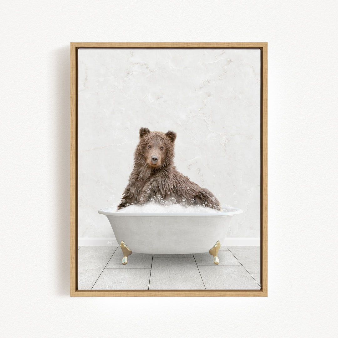 A brown bear sitting in a white bathtub filled with bubbles, looking directly at the camera.