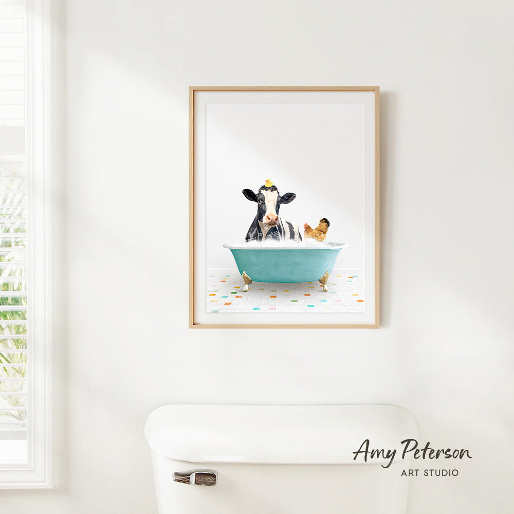 A framed image of a cow sitting in a bathtub, with a chicken nearby, is hanging on a white wall.