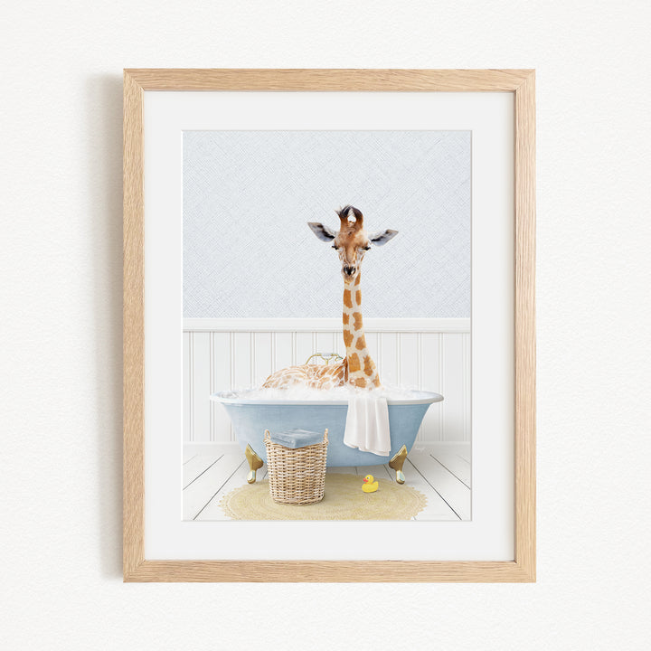 A giraffe sitting in a blue bathtub filled with bubbles, surrounded by a basket of toys and a yellow rubber duck.