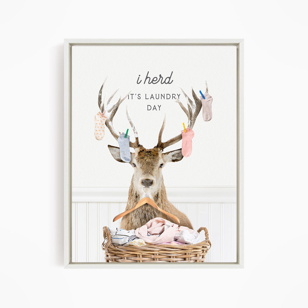 A deer with antlers is sitting in a wicker basket, surrounded by laundry, with the text "I herd, it's laundry day" displayed above the deer.