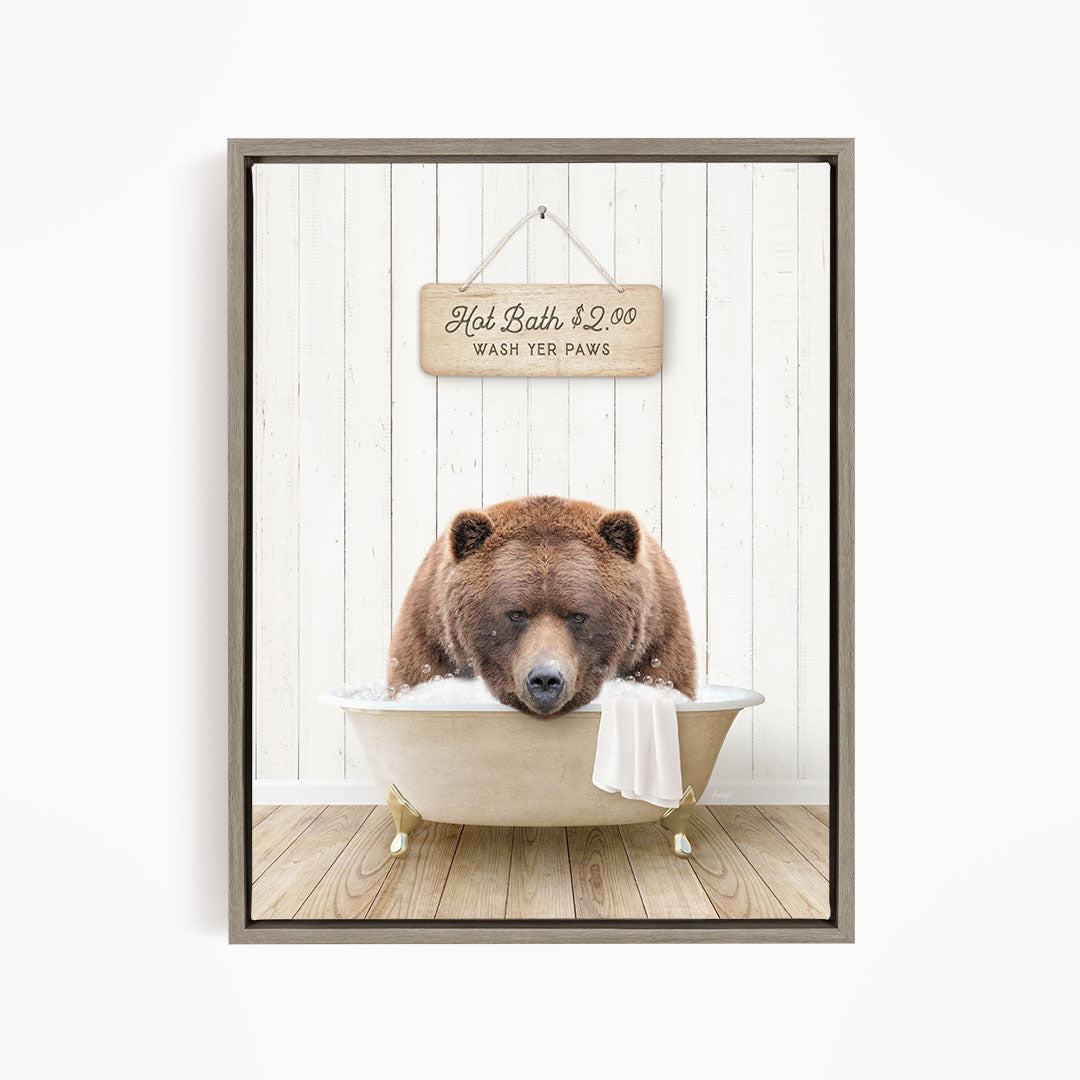 A brown bear sitting in a bathtub, with a sign above it that says "Hot Bath $2.00 WASH YOUR Paws".