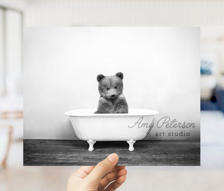 a black and white photo of a baby bear in a bathtub