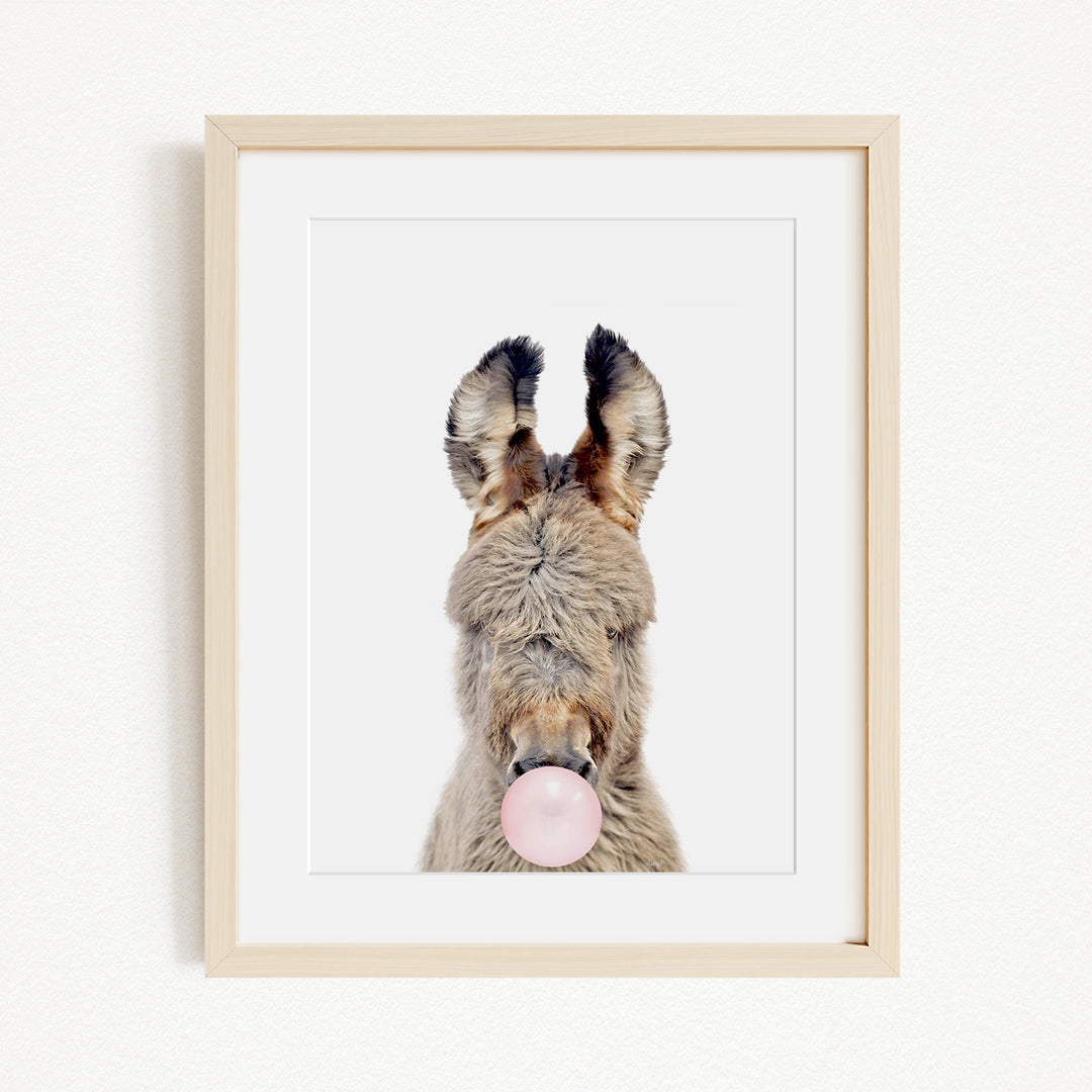 A donkey with its head tilted upwards and a pink bubble blowing in its mouth.
