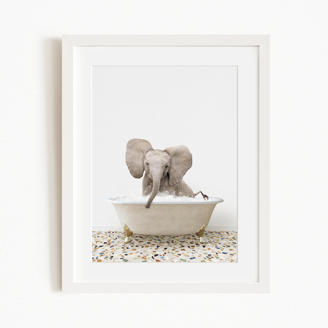 A baby elephant sitting in a white bathtub filled with water, with its trunk submerged in the water.