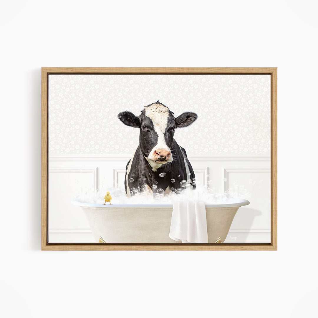 A black and white cow is sitting in a bathtub filled with bubbles, with a yellow bird perched on the edge of the tub.