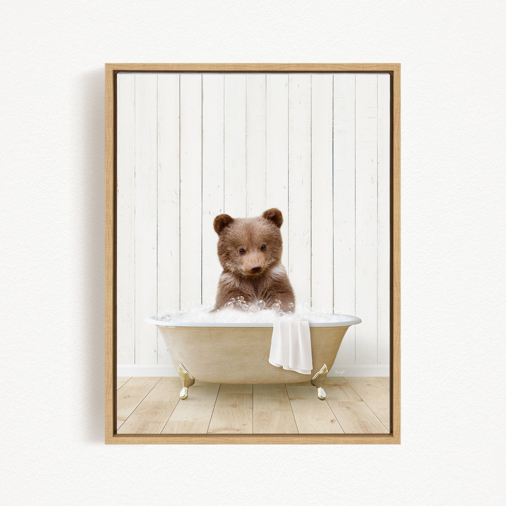 A brown bear sitting in a white bathtub filled with water, with a towel hanging on the side of the tub.