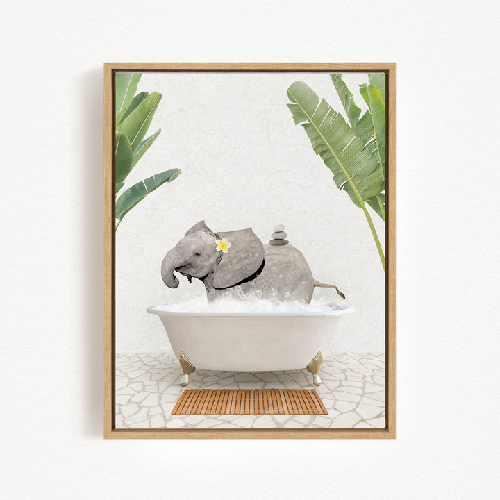 A gray elephant is sitting in a white bathtub filled with water, surrounded by green leaves and a wooden mat on the floor.