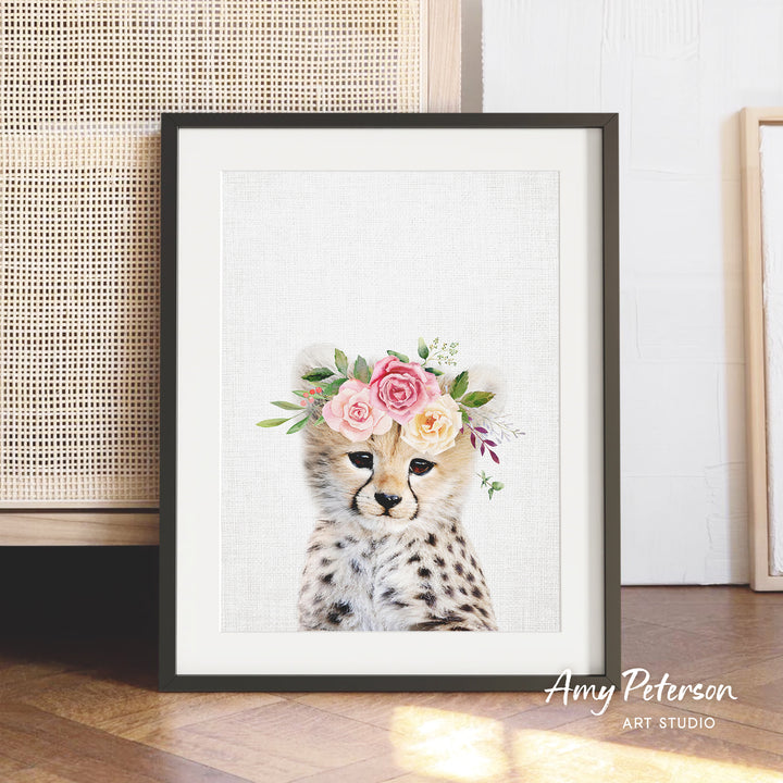 A framed print of a cheetah wearing a floral crown, with a white background and pink and white flowers.