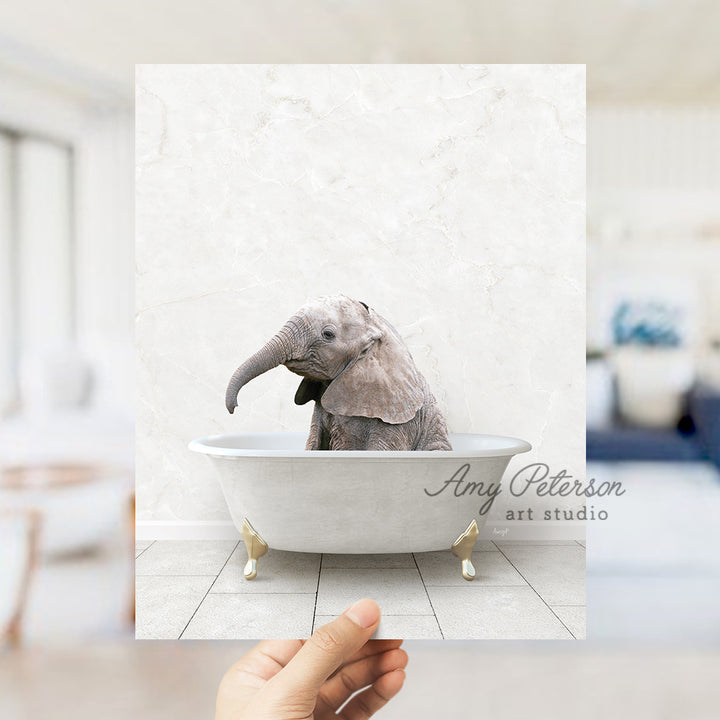 a hand holding up a picture of an elephant in a bathtub