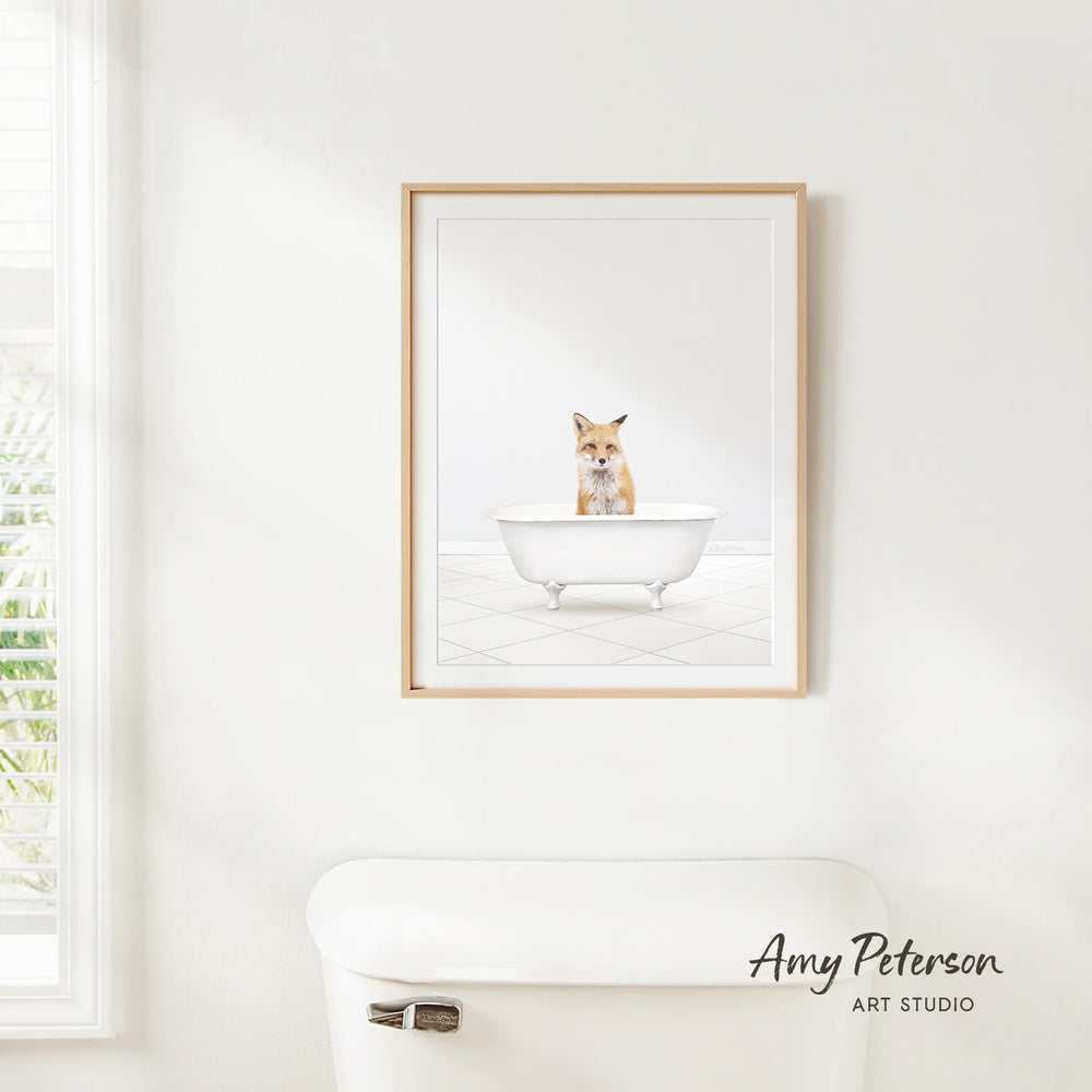 A framed image of a cat sitting in a bathtub, with a window and a toilet visible in the background.