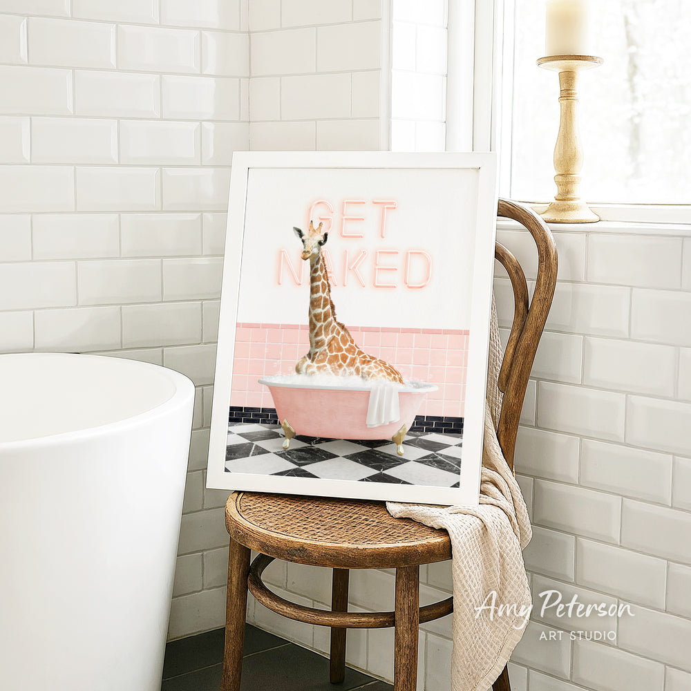 A framed image of a giraffe sitting in a pink bathtub, with the text "GET NAKED" displayed on the frame.