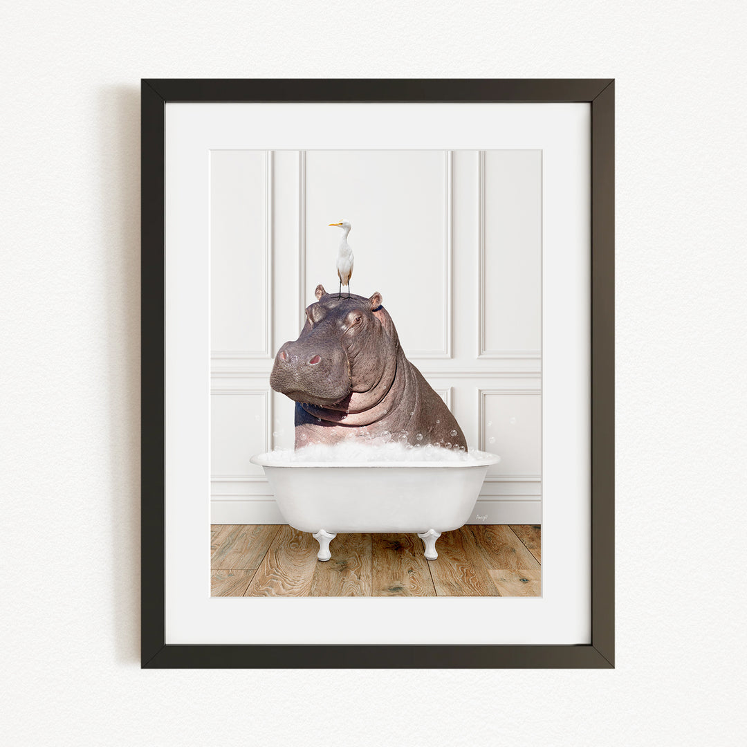A framed image depicting a hippopotamus sitting in a bathtub, with a seagull perched on its head.