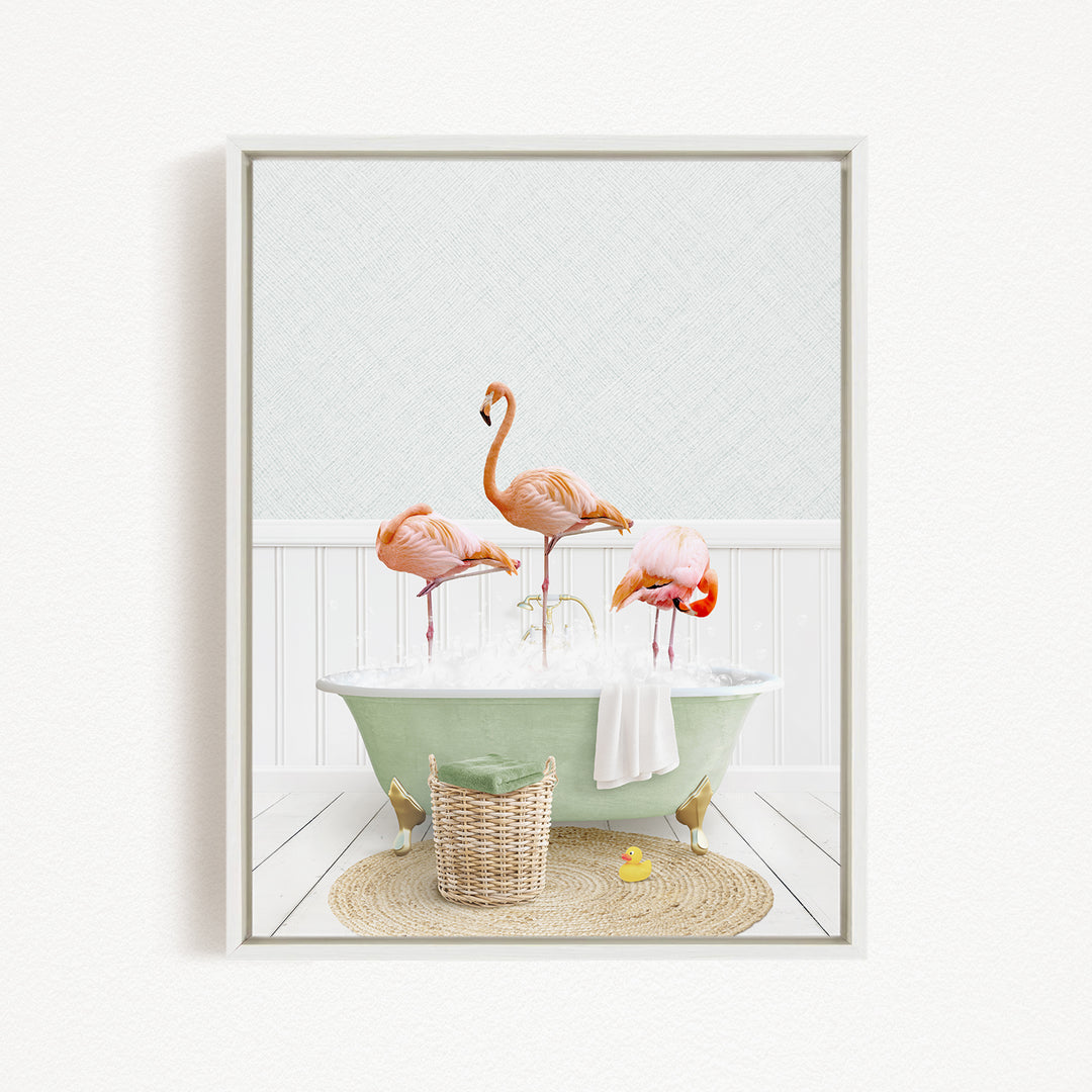 A framed image depicting three flamingos standing in a green bathtub filled with bubbles, surrounded by a basket of bath toys and a yellow rubber duck.
