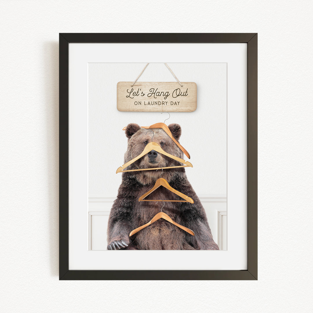 A framed image of a bear holding a sign that says "Let's Hang Out on Laundry Day".