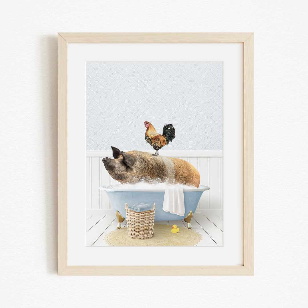 A framed image depicting a pig sitting in a bathtub, with a rooster perched on its back, and a basket of rubber ducks nearby.