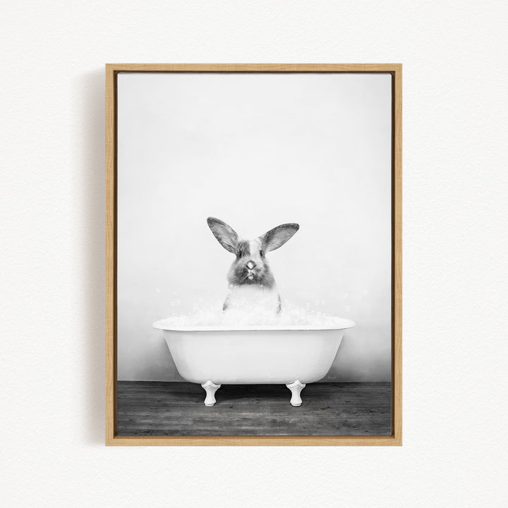 A black and white photograph of a rabbit sitting in a bathtub filled with water.